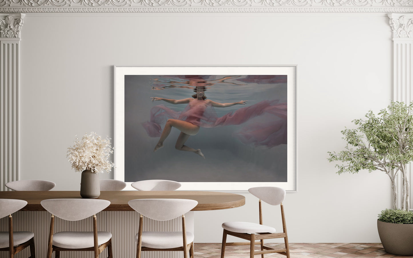 Within the depths of the sea, a stunning figure, wrapped in sheer pink chifon, floats gracefully amidst the aquatic realm. Her ethereal beauty and serene presence are accentuated by the play of light and shadow in the fine art photography. The mysterious allure of the underwater world surrounds her, evoking a sense of enchantment and tranquility